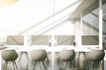 Front view of modern coworking office with multiple blank computers. Toned image. Mock up, 3D Renderingの写真素材