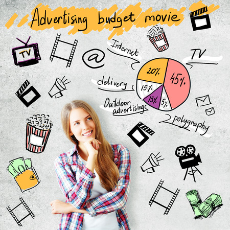 Attractive young woman on concrete background with cinematography related drawings. Advertising budget movie conceptの写真素材