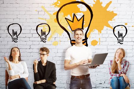 Young team on brick background with drawn light bulbs. New business ideas