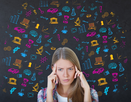Pensive young european woman on dark background with education doodles. College concept