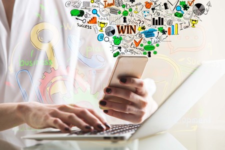 Side view of female hands using laptop and smartphone with creative business sketch, placed on glass...
