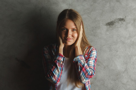 Portrait of attractive cheerful young woman on concrete wall backgroundの写真素材