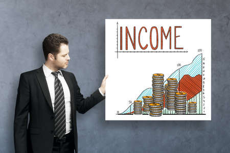Handsome young businessman on concrete background with income sketch on poster