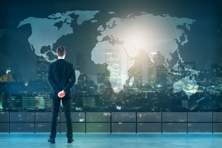 Back view of young businessman on rooftop looking at abstract map. Night city background. Travel conceptの写真素材