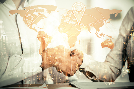 Women shaking hands at workplace with map and city view. Double exposure. Global business conceptの写真素材
