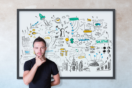Thoughtful young male with business sketch in frame on concrete wall background. Achievement conceptの写真素材
