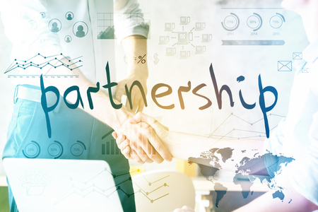 Close up of handshake at bright workplace with laptop and business charts. Partnership conceptの写真素材