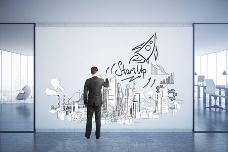 Back view of young businessman drawing creative in concrete office interior with city view. Progress concept. 3D Renderingの写真素材