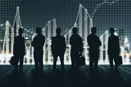 Businessmen silhouettes on city background with business charts. Teamwork concept. Double exposureの写真素材
