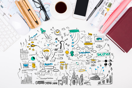 Top view of white office desktop with supplies, devices, coffee cup and colorful business sketch. Solution conceptの写真素材