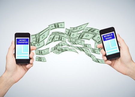 Mobile bank concept. Hands holding two cellphones with abstract dollar flow. Gray background. 3D Renderingの写真素材