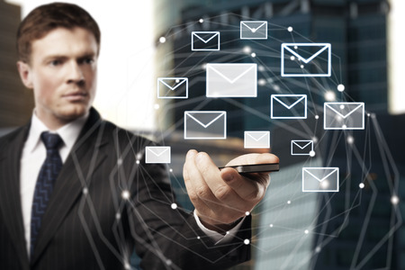 Handsome european businessman holding smartphone with email network on blurry backgroundの写真素材