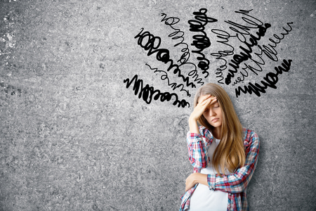 Pensive young woman on concrete background with scribble. Confusion conceptの写真素材