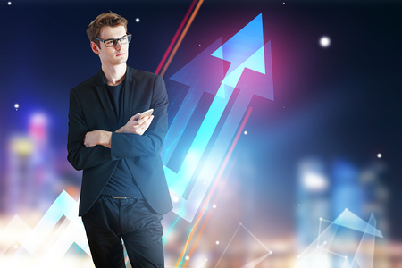 Businessman holding smartphone on blurry night city background with glowing chart arrows. Financial growth concept. Double exposureの写真素材