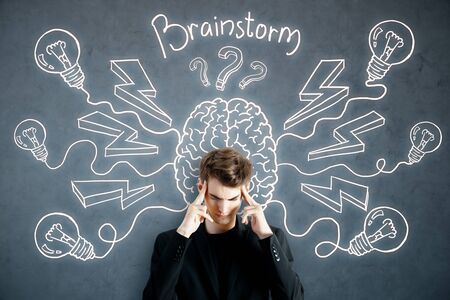 Pensive young man on concrete background with abstract brain sketch. Brainstorm and imagination...