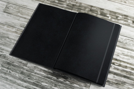 Empty black notepad on wooden desktop. Advertisement, supplies, education, text, copy space concept. Mock up, 3D Renderingの写真素材