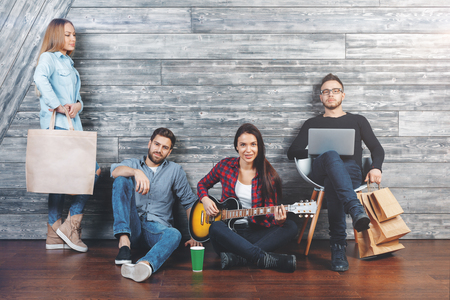 Happy friends playing the guitar, having fun and communicating at home in wooden interior. Music group conceptの写真素材