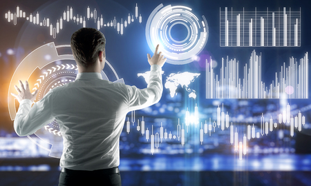 Back view of young businessman managing abstract business forex hologram on blurry night city background. Future and finance concept. Double exposureの写真素材