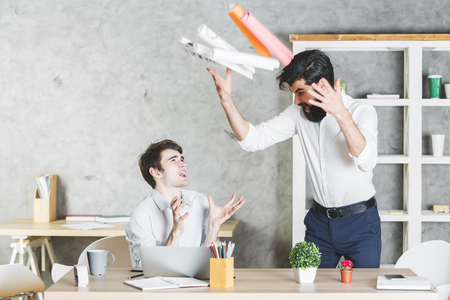 Crazy frustrated handsome businessmen colleagues in modern office interiorの写真素材