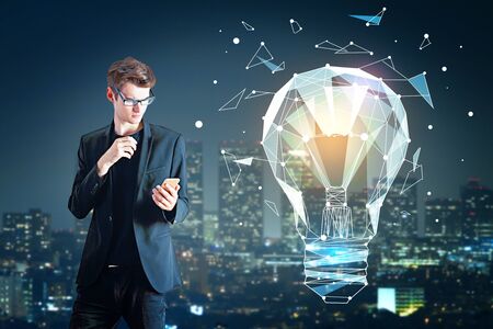 Handsome businessman using smartphone on abstract night city background with polygonal lamp....