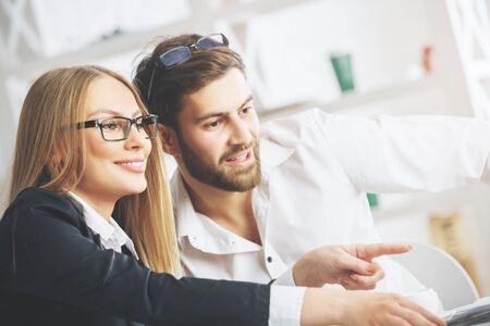 Side portrait of pointing european man and woman in blurry office. Teamwork and partnership conceptの写真素材