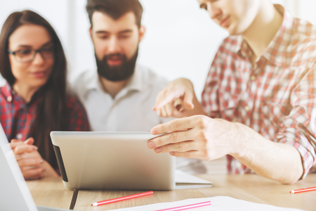 European woman and men using pad tablet mobile device and doing paperwork at office desk. Teamwork and technology conceptの写真素材