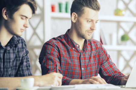 Portrait of two attractive european gentlemen working on project at workplace. Team work conceptの写真素材