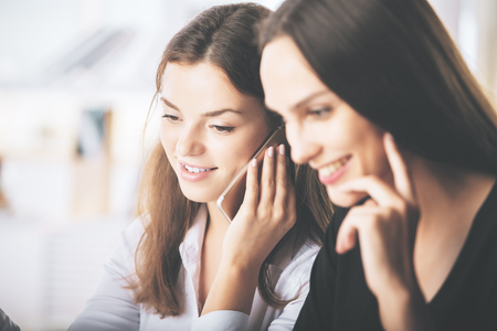 Close up portrait of two attractive caucasian ladies talking on phoneの写真素材