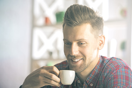 Close up portrait of attractive smiling man in casual shirt with coffee cupの写真素材