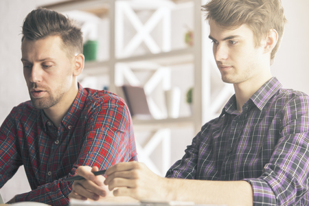 Portrait of two handsome caucasian boys doing paperwork in modern office. Team work conceptの写真素材