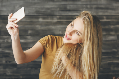 Portrait of pretty european female taking selfie with smartphone. Technology, modern conceptの写真素材
