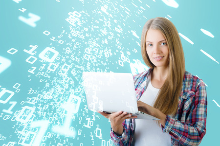 Attractive smiling young european woman using laptop on blue background with abstract binary code. Coding conceptの写真素材