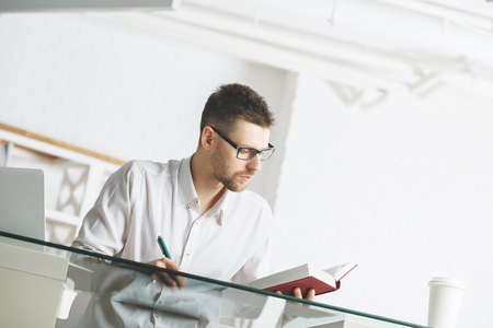 Portrait of caucasian businessman working on project at modern office desktop with items. Job, occupation, lifestyle concept の写真素材