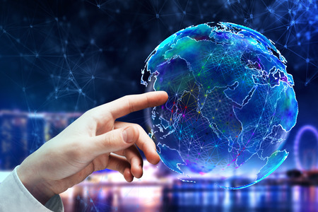 Hand pointing at abstract polygonal globe on blurry night city background. Global business and...