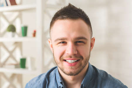 Close up portrait of smiling young businessman on blurry office backgroundの写真素材