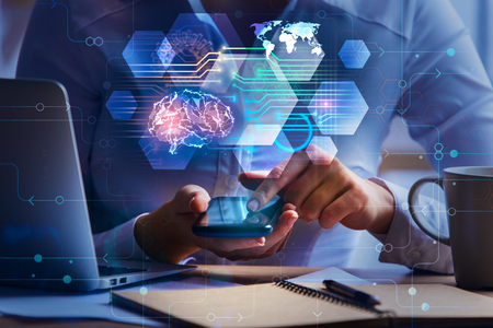 Close up of businesswoman hands using smartphone and office desk with laptop, coffee cup, notepad and abstract brain interface hologram. Artificial intelligence and technology concept. Double exposure の写真素材