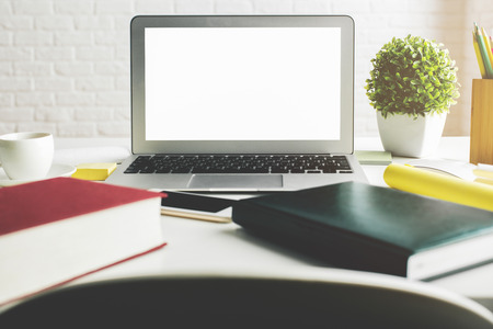 Close up of creative designer desktop with empty white laptop monitor, smartphone, supplies and other items. Office, education, occupation, freelance and lifestyle concept. Mock up の写真素材