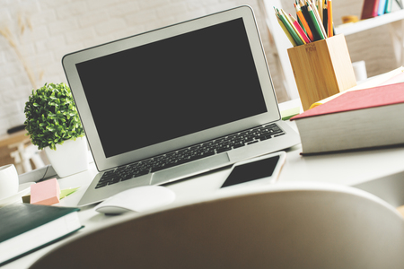 Modern desktop with empty laptop screen, smartphone, supplies and other items. Creative designer office, education, occupation, freelance and lifestyle concept. Mock up の写真素材