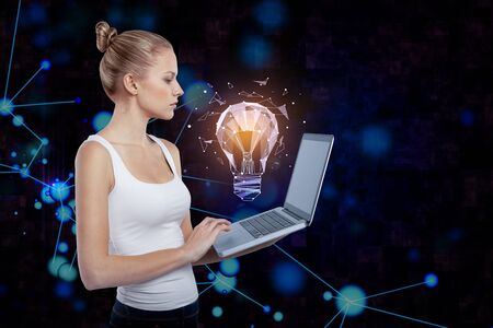 Side view of attractive european woman using laptop with abstract glowing polygonal lamp and...