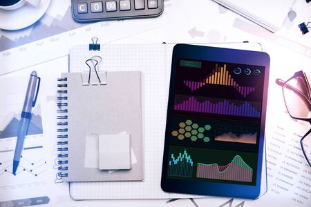 Top view and close up of creative office workplace with business charts on tablet screen and...