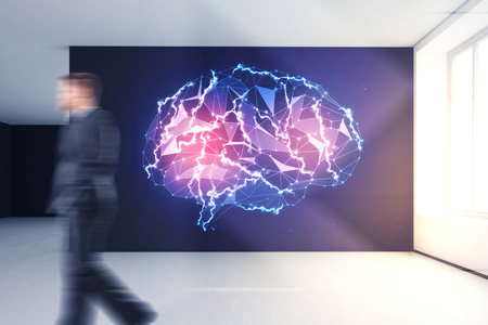 Blurry businessman walking past wall with glowing polygonal brain gologram in empty interior....
