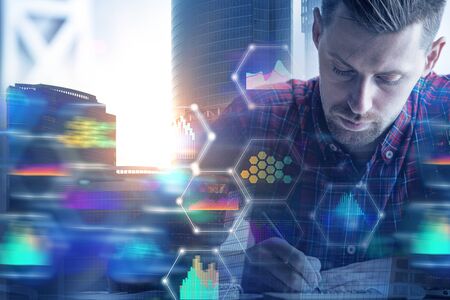 Businessman doing paperwork on abstract city background with blurry business hologram. Innovation concept. Double exposure の写真素材