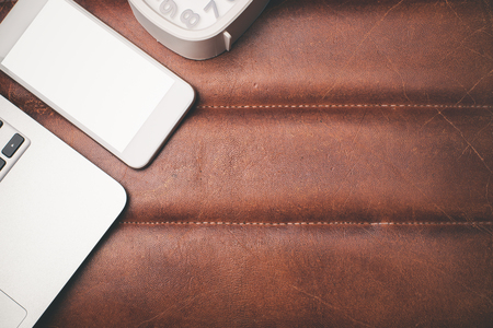 Top view of leather surface desk with blank smartphone, laptop keyboard, clock and copy space. Mock upの写真素材