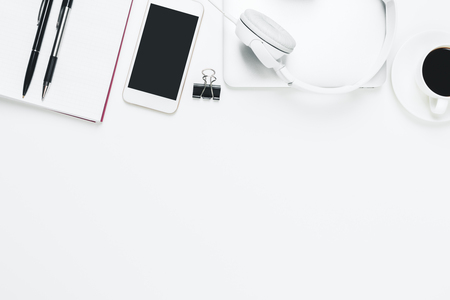 Top view and close up of modern white office desktop with empty smartphone, supplies, headphones and other items. Leisure, hobby, break, work and occupation concept. Mock upの写真素材