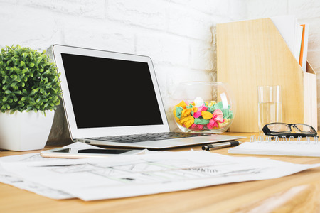 Close up of creative designer table with blank laptop, smartphone, supplies and other items. Technology and device concept. Mock up の写真素材