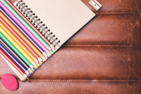 Top view of brown leather desktop with colorful supplies and copy space. School and equipment conceptの写真素材