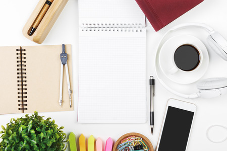 Top view and close up of creative white office desk top with empty smartphone, supplies, headphones...