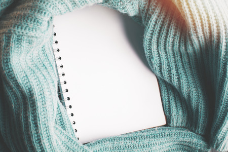 Close up of empty spiral notepad wrapped in knitted cloth. Cozy workplace concept. Mock upの写真素材