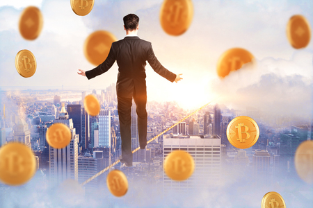 Back view of young businessman walking on abstract city background with golden bitcoin rain. Cryptocurrency and finance conceptの写真素材