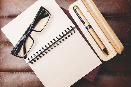 Close up and top view of empty spiral notepad placed on leather office desk. Letter, paperwork and equipment concept. Mock up の写真素材
